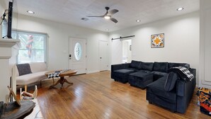 A spacious living room with hardwood flooring, a sectional sofa, a small table, and a ceiling fan. - Easy Access to Osu! 'marvin's Manor' in Stillwater (Stillwater)