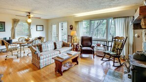 A cozy living room with a wooden floor, a plaid sofa, a rocking chair, and a fireplace. - Ski, Hike & Unwind: Mtn-view Gem w/ Deck in Boone (Boone)