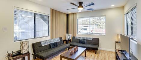 A modern living room with a sectional sofa, a coffee table, and a flat-screen TV.
