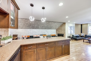 Una cocina con encimeras de granito, armarios de madera e iluminación colgante.
