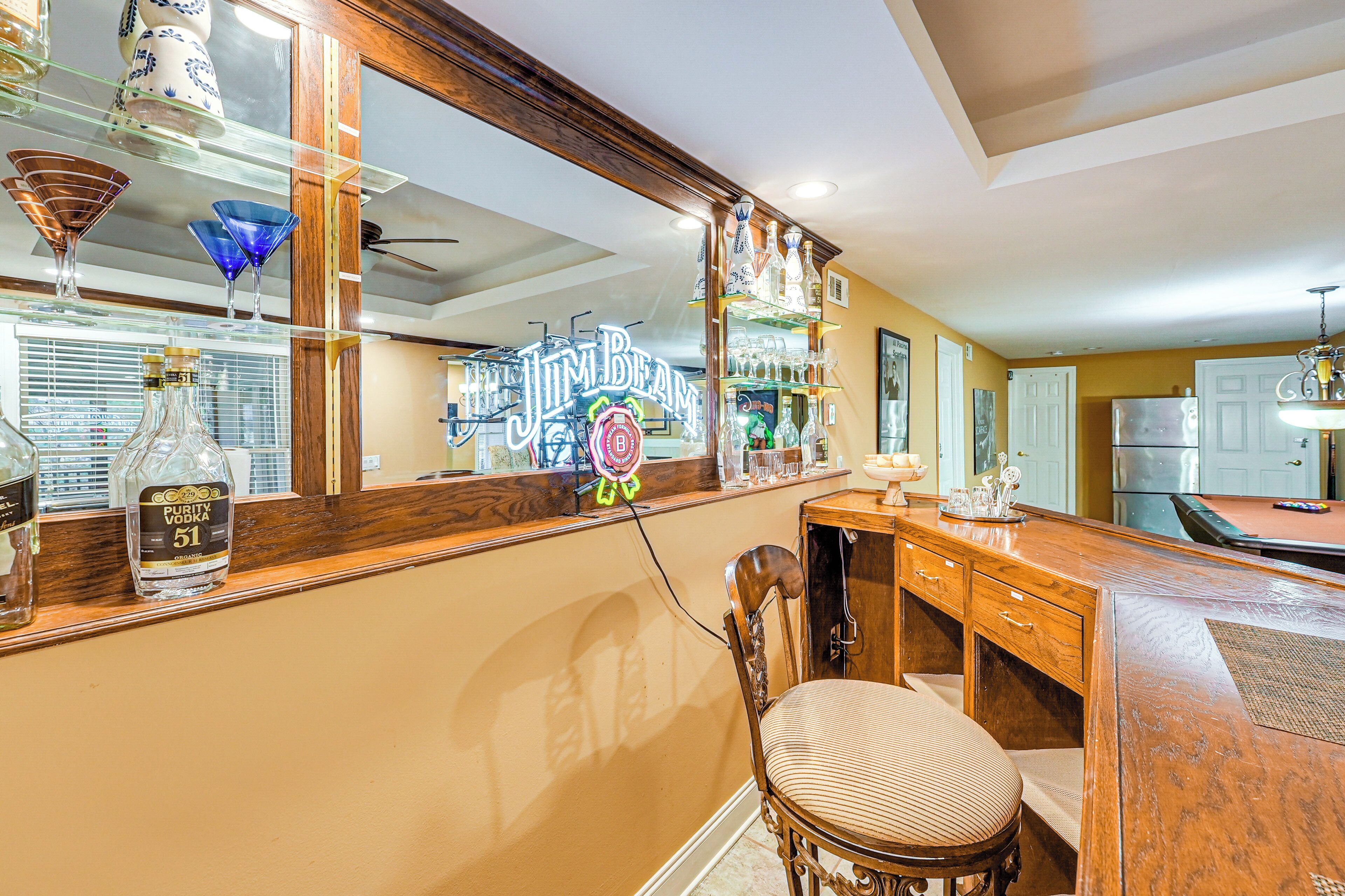 Zona de bar con mostrador de madera, una silla y un letrero de neón.
