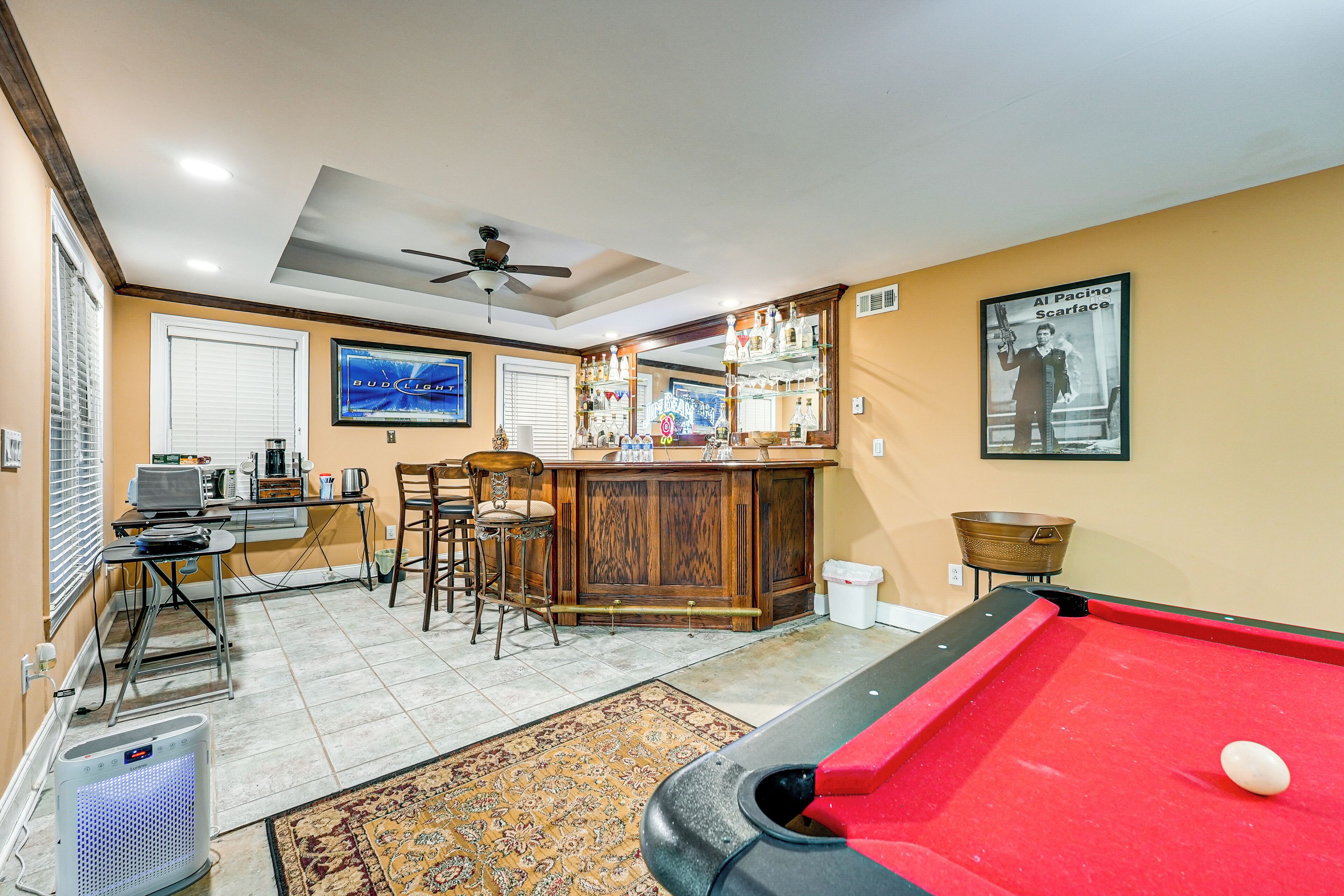 A pool table, bar area, and seating with a ceiling fan.