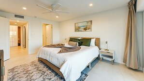 Ein modernes Schlafzimmer mit einem großen Bett, einem Nachttisch, einem Deckenventilator und einem Bild an der Wand.