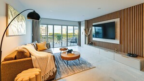 Ein modernes Wohnzimmer mit einer Couch, einem Couchtisch und einem an einer Holzwand befestigten Fernseher.