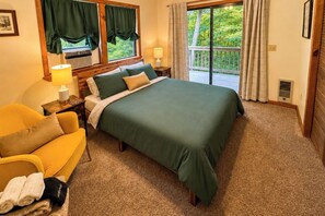 A hotel room with a bed, a yellow armchair, a nightstand with a lamp, and a window with curtains. - Mtn-view Deck! Maggie Valley Cabin, 8 Mi to Skiing (Maggie Valley)