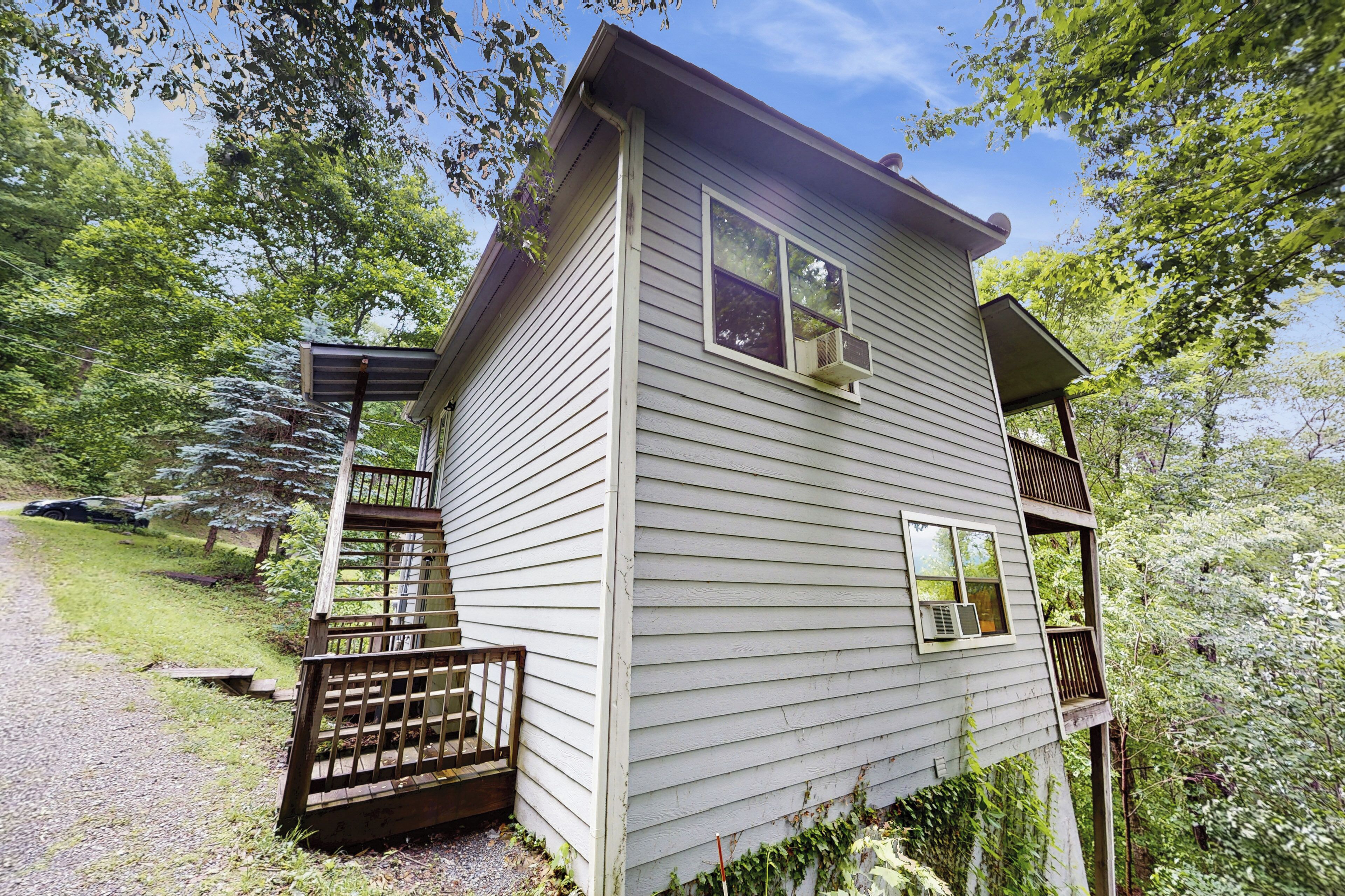 A two-story house with a wooden deck and a covered porch.