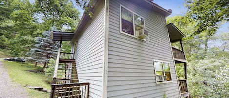 A two-story house with a wooden deck and a covered porch.