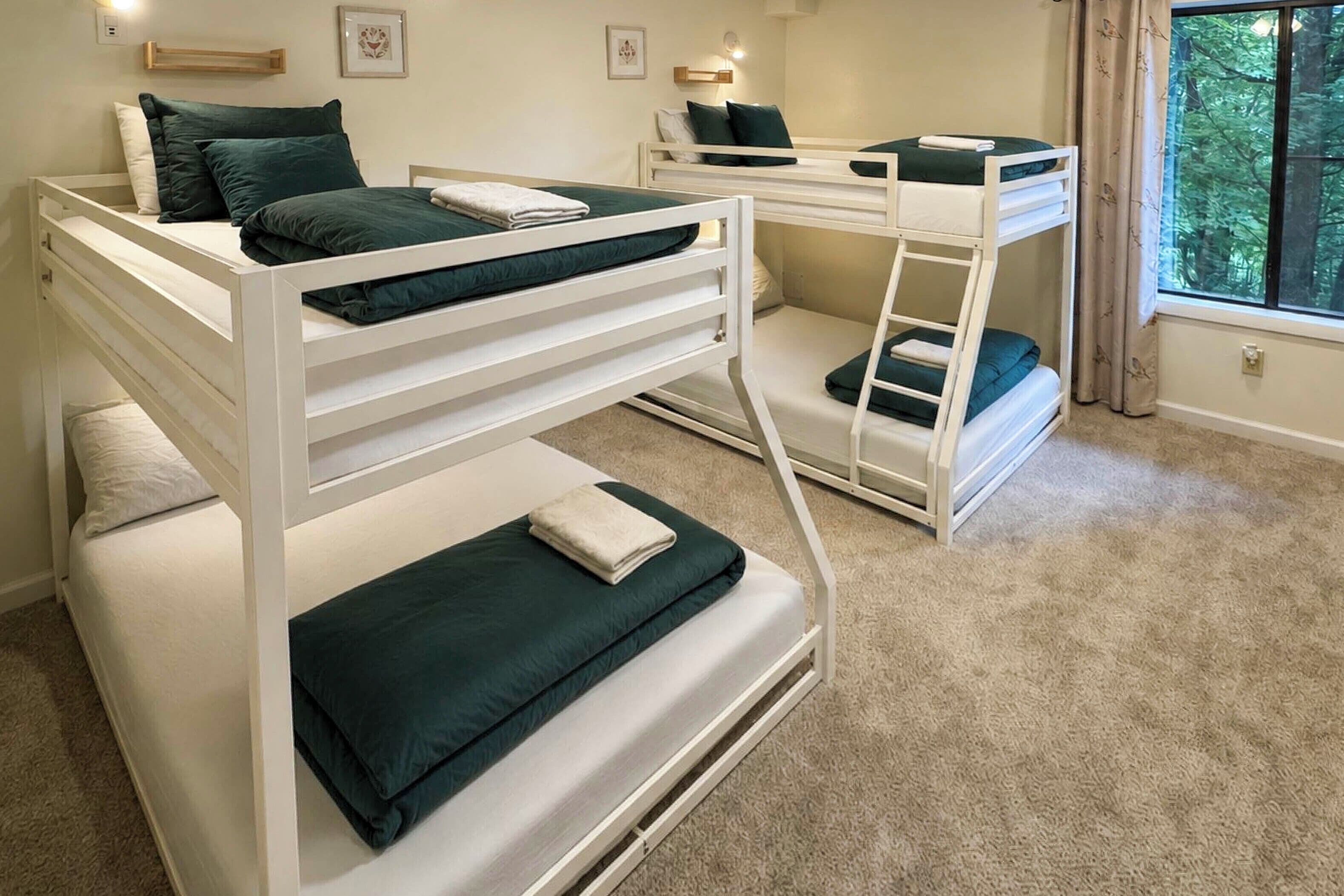 A room with bunk beds, a window with curtains, and a carpeted floor.