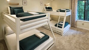 Una habitación con literas, una ventana con cortinas y suelo alfombrado.