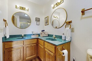 Un baño con dos lavamanos, armarios de madera y varios espejos.