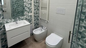 Ein modernes Badezimmer mit Dusche, Bidet, Toilette und einem großen Spiegel.