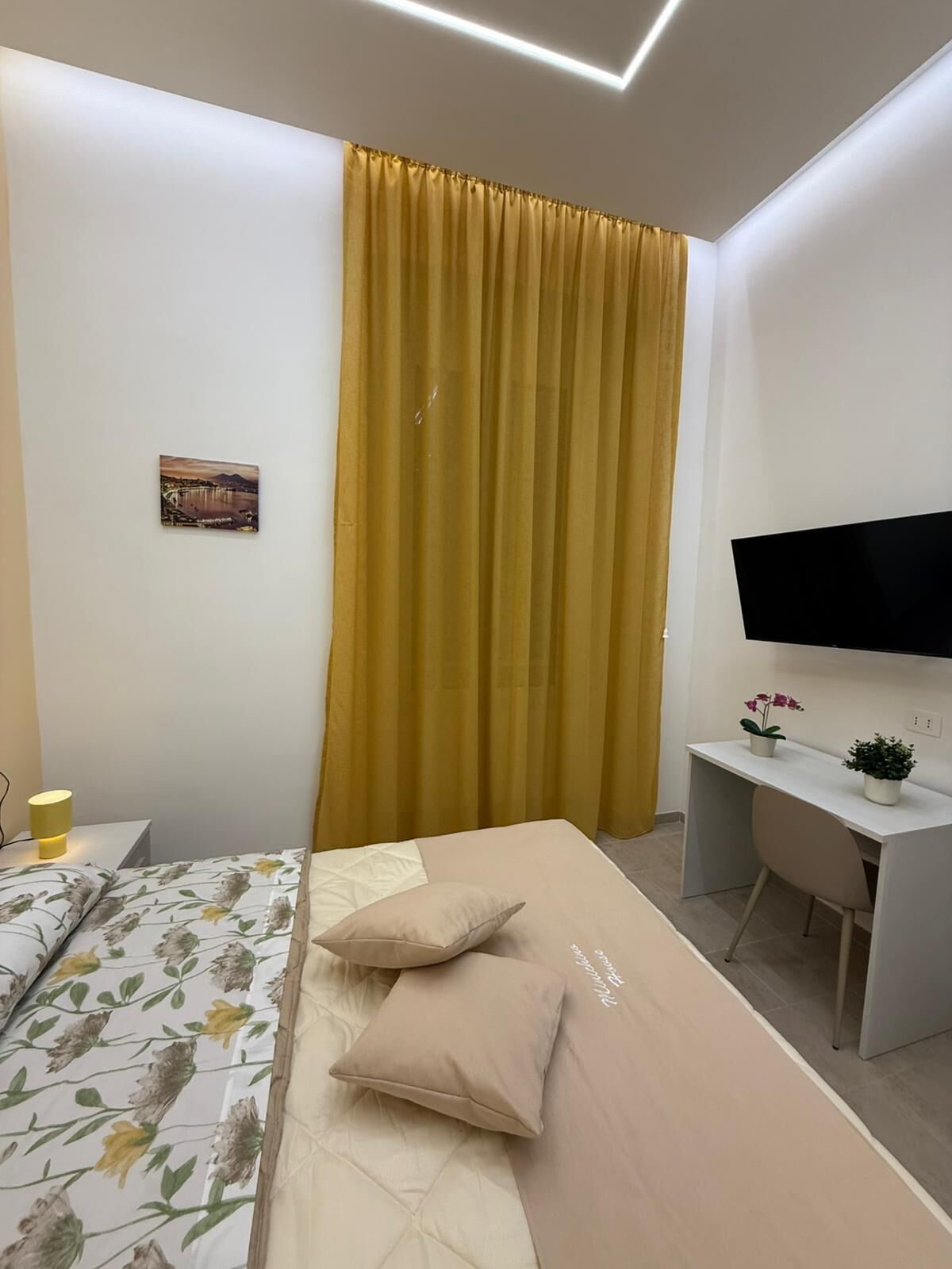 Une chambre d’hôtel moderne équipée d’un lit, d’un bureau, d’une télévision et d’une grande fenêtre avec des rideaux.