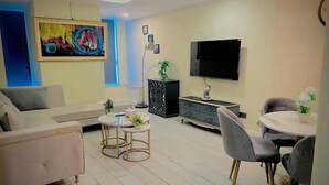 Una sala moderna con un sofá, dos mesas redondas, un televisor y un cuadro en la pared.