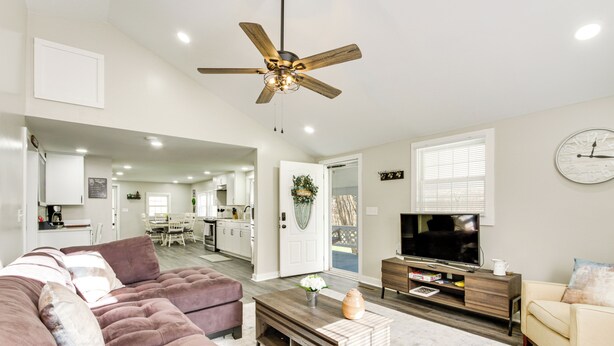 A modern living room with a large sofa, a coffee table, a TV, and a ceiling fan. - Secluded Getaway on 40 Acres in Lawrenceburg! (Lawrenceburg)