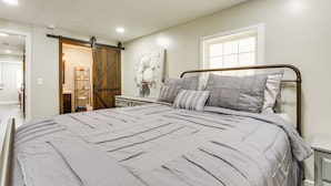A bedroom with a large bed, a wooden wardrobe, a nightstand, and a window with blinds. - Secluded Getaway on 40 Acres in Lawrenceburg! (Lawrenceburg)