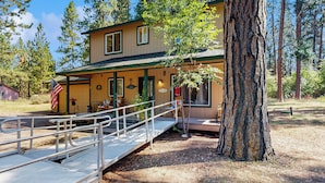 A lodge with a covered porch, a small outdoor seating area, and a flag. - Access to Latakomie Shores Lakefront Park! (Chiloquin)