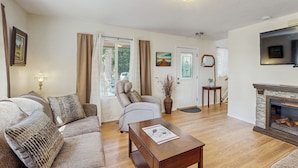 A living room with a sofa, armchair, coffee table, fireplace, TV, and a door with a mirror. - Access to Latakomie Shores Lakefront Park! (Chiloquin)