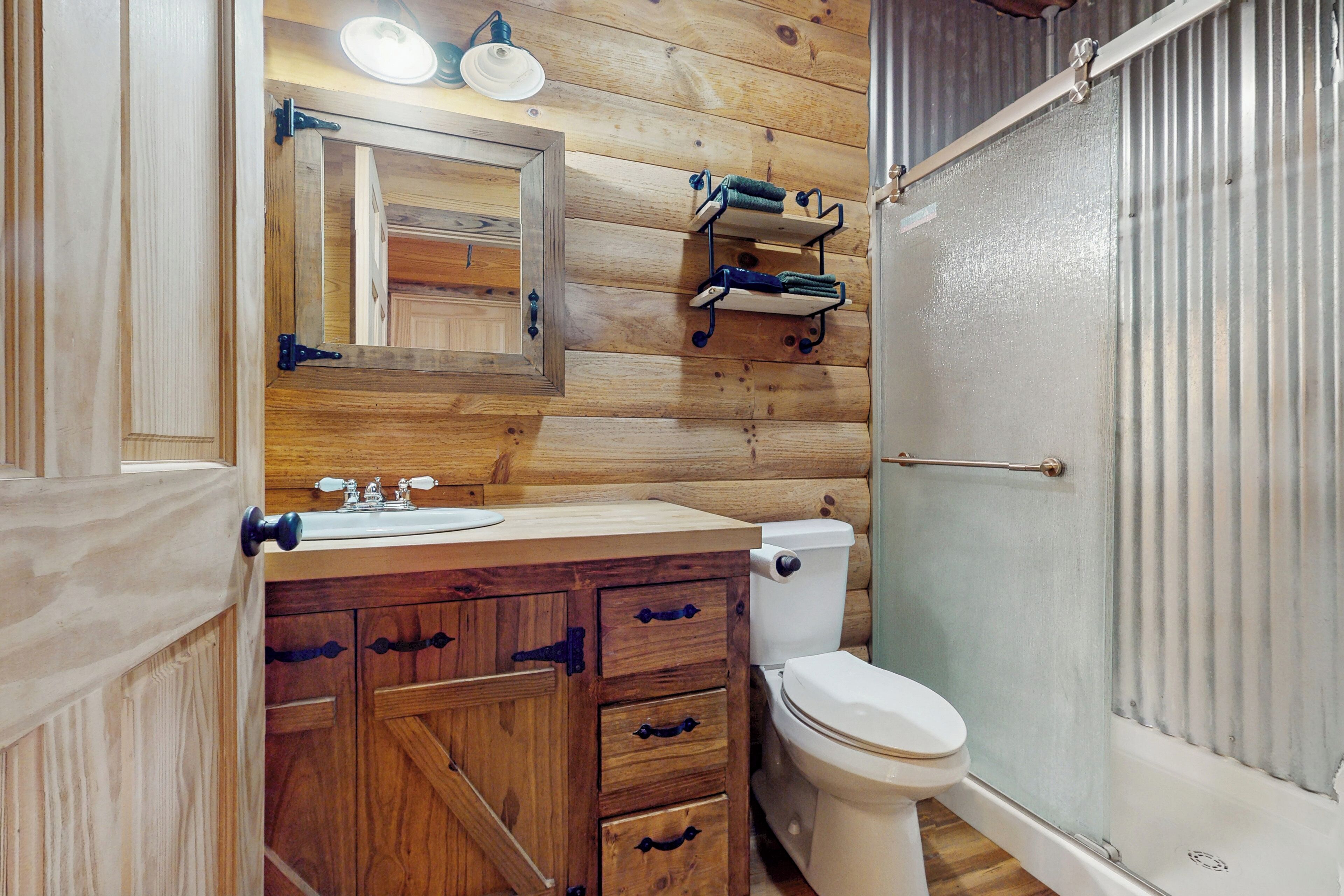 Un baño de madera con lavamanos, espejo e inodoro.