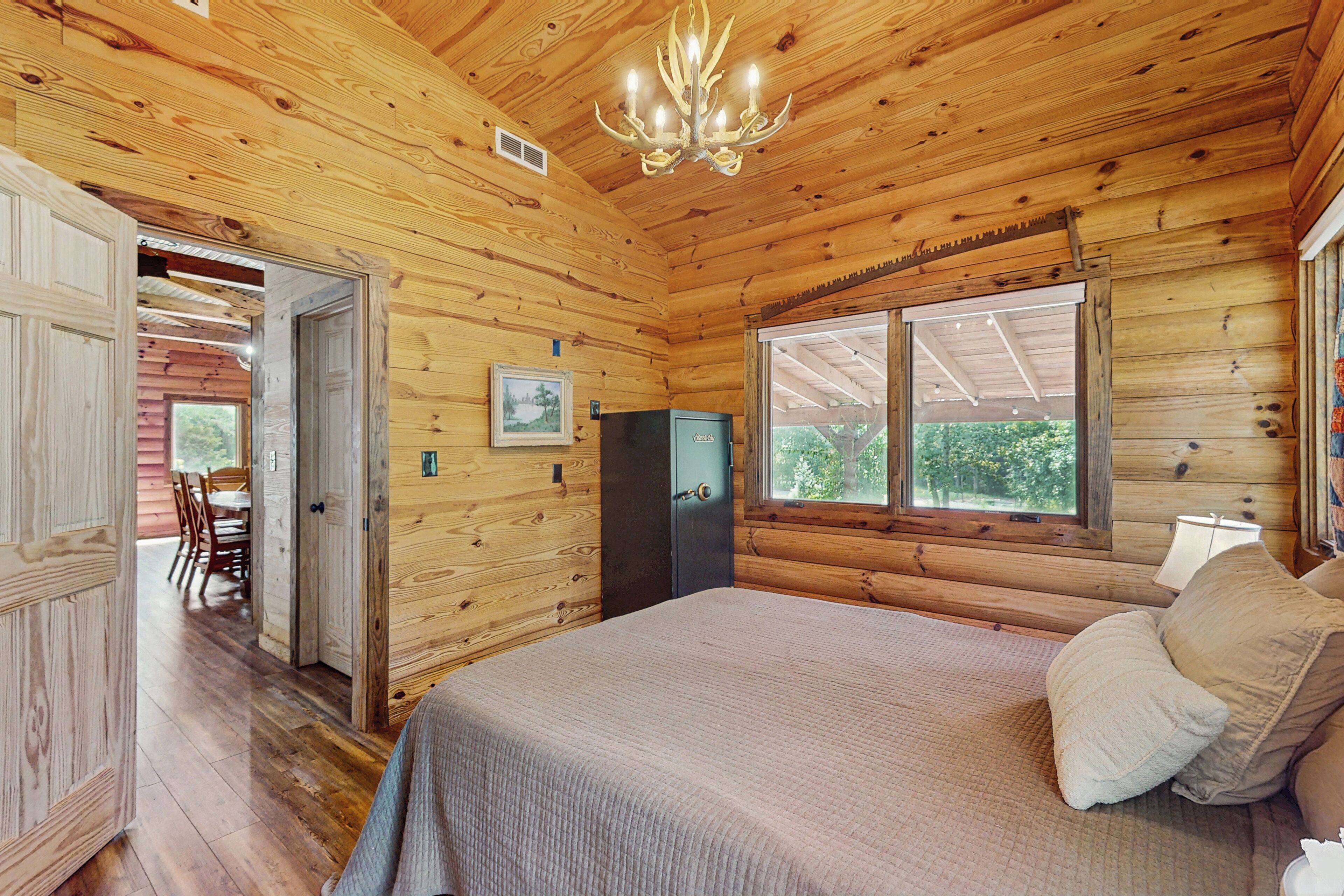 Un dormitorio de cabaña de madera con una cama, un tocador, un escritorio y una ventana.