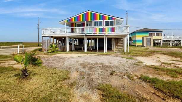 Una casa de dos pisos con fachada colorida, un balcón y un porche cubierto.