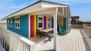 Una casa de playa colorida con un muelle de madera y una mesa de picnic.