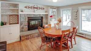 A dining area with a stone fireplace, wooden chairs, and a white cabinet with glassware. - 5 Mi to Mt Snow: Secluded Family Home w/ Game Area (West Dover)