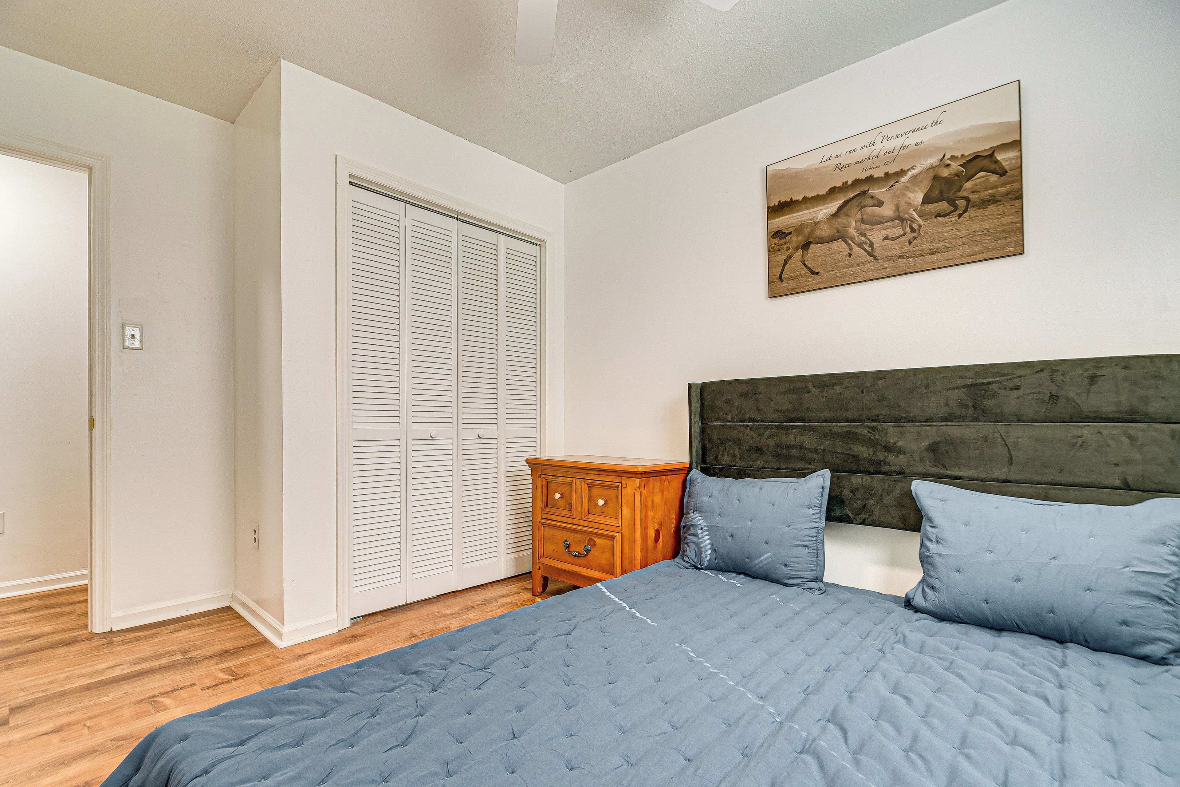 A bedroom with a bed, a wooden nightstand, a wardrobe, and a painting on the wall.