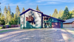 A two-story building with a balcony, a garage, and a gravel driveway. - Creekside Escape w/ Private Hot Tub in Shingletown (Shingletown)