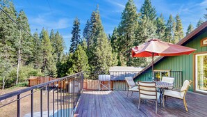 A wooden deck with a metal railing, a table with chairs, and a red umbrella. - Creekside Escape w/ Private Hot Tub in Shingletown (Shingletown)