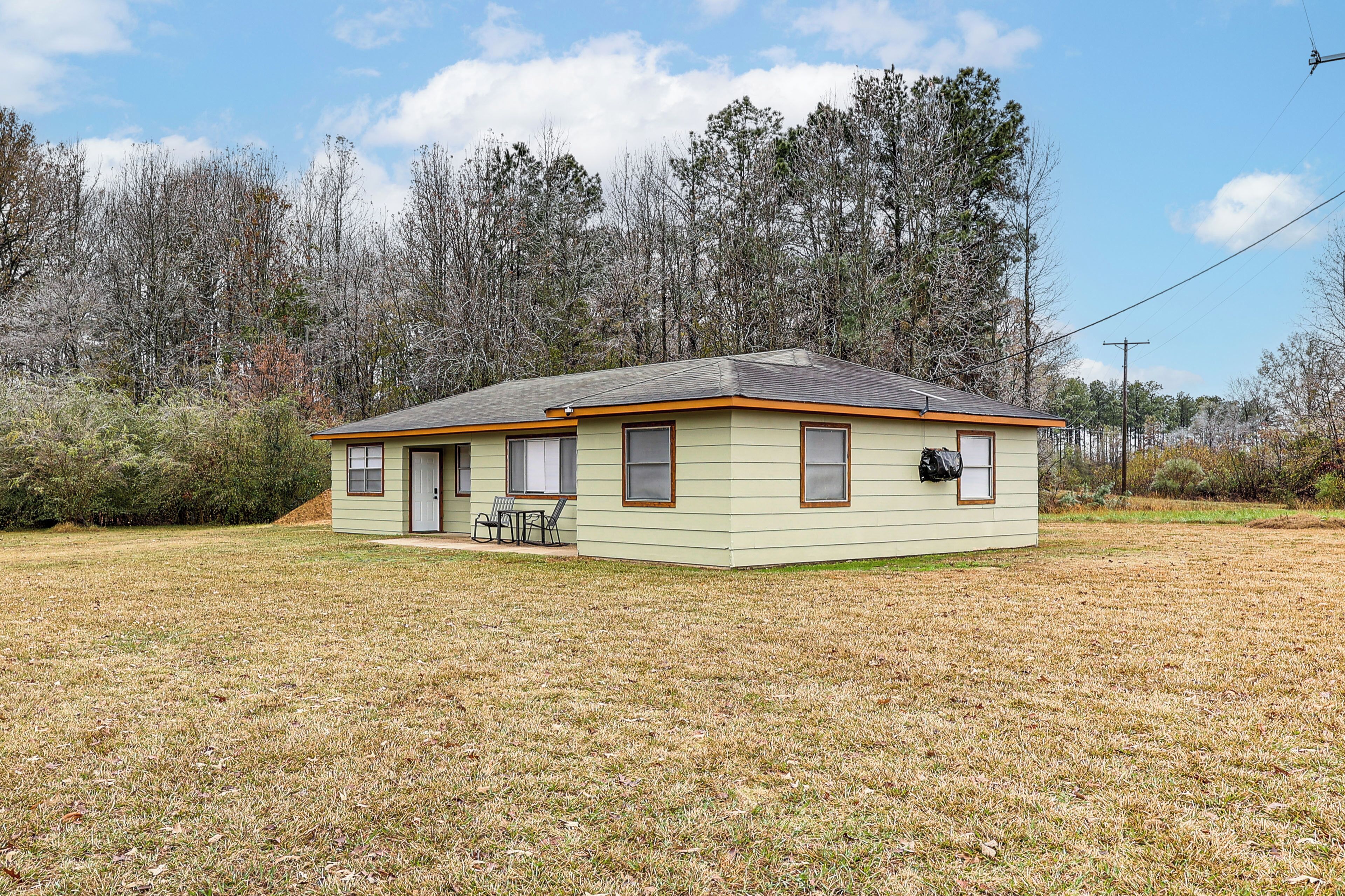 A single-story house with a flat roof, a front porch with a bench, and a small attached garage.