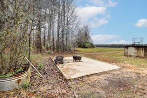 An outdoor area with a concrete patio, a metal barrel, and a wooden tub.