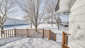 A snow-covered outdoor area with a wooden fence, trees, and a building in the background. - Spacious Retreat w/ Private Yard & Deck in Roscoe! (Roscoe)
