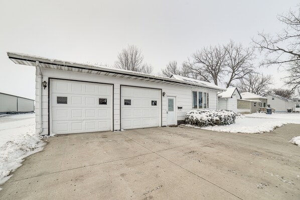 A residential garage with two white doors, a concrete driveway, and a snow-covered landscape. - Spacious Retreat w/ Private Yard & Deck in Roscoe! (Roscoe)