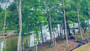 A serene lakeside area with tall trees and a dock extending into the water. - 4BR Lakefront Retreat w/ Furnished Deck, Dock (Salisbury)