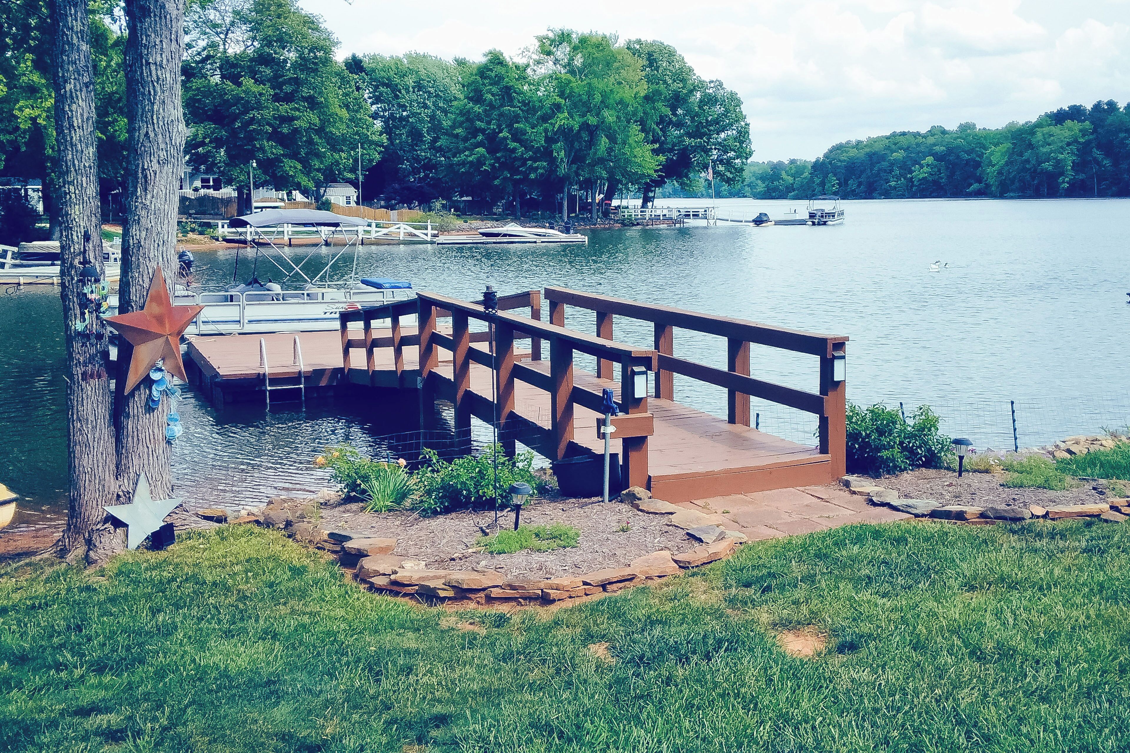 A wooden dock extending into a lake with boats docked nearby.