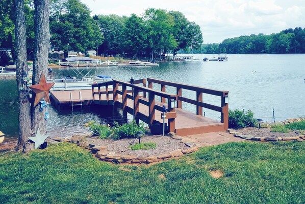 A wooden dock extending into a lake with boats docked nearby.