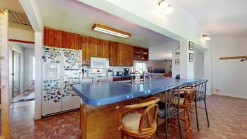 A kitchen with wooden cabinets, a blue countertop, and a bar seating area with wicker chairs.