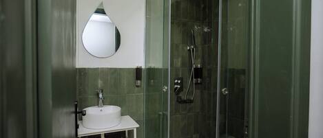 Een moderne badkamer met een douchecabine van glas, een wit wastafelmeubel en een spiegel.
