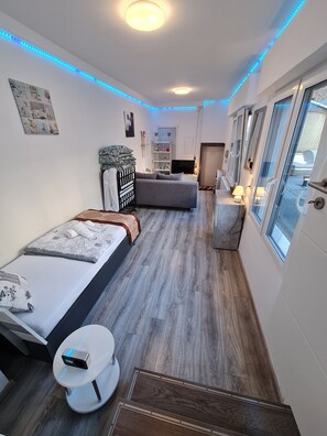 Une chambre d’hôtel de taille réduite, comprenant un lit, une table de chevet et un petit coin salon.
