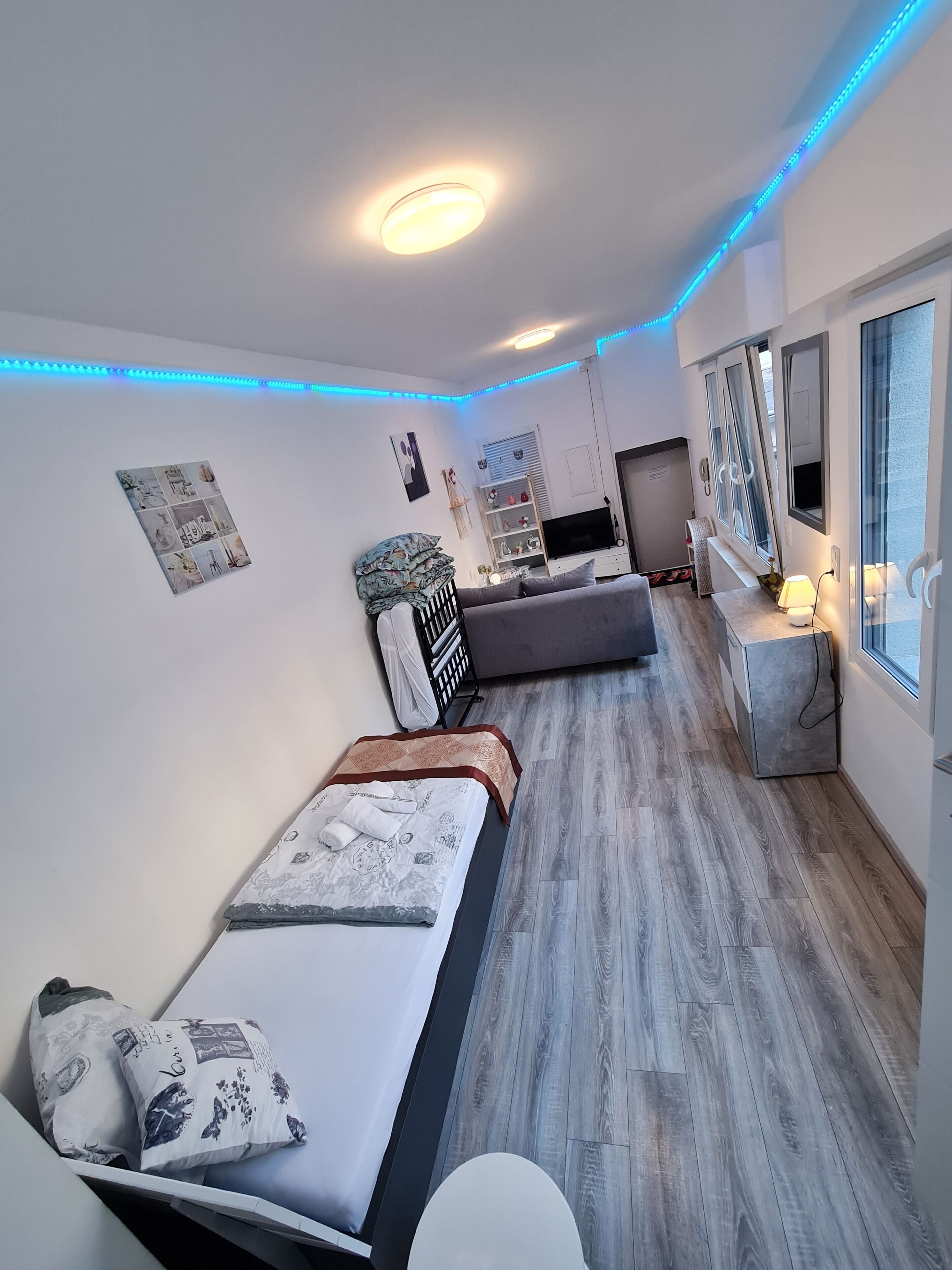 A modern bedroom with two beds, a TV, and a bedside table with a lamp.. Cityapartment +terrace up to 4 persons Neuwied city center Rheinprominade
