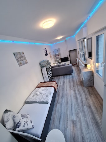 A modern bedroom with two beds, a TV, and a bedside table with a lamp.. Cityapartment +terrace up to 4 persons Neuwied city center Rheinprominade