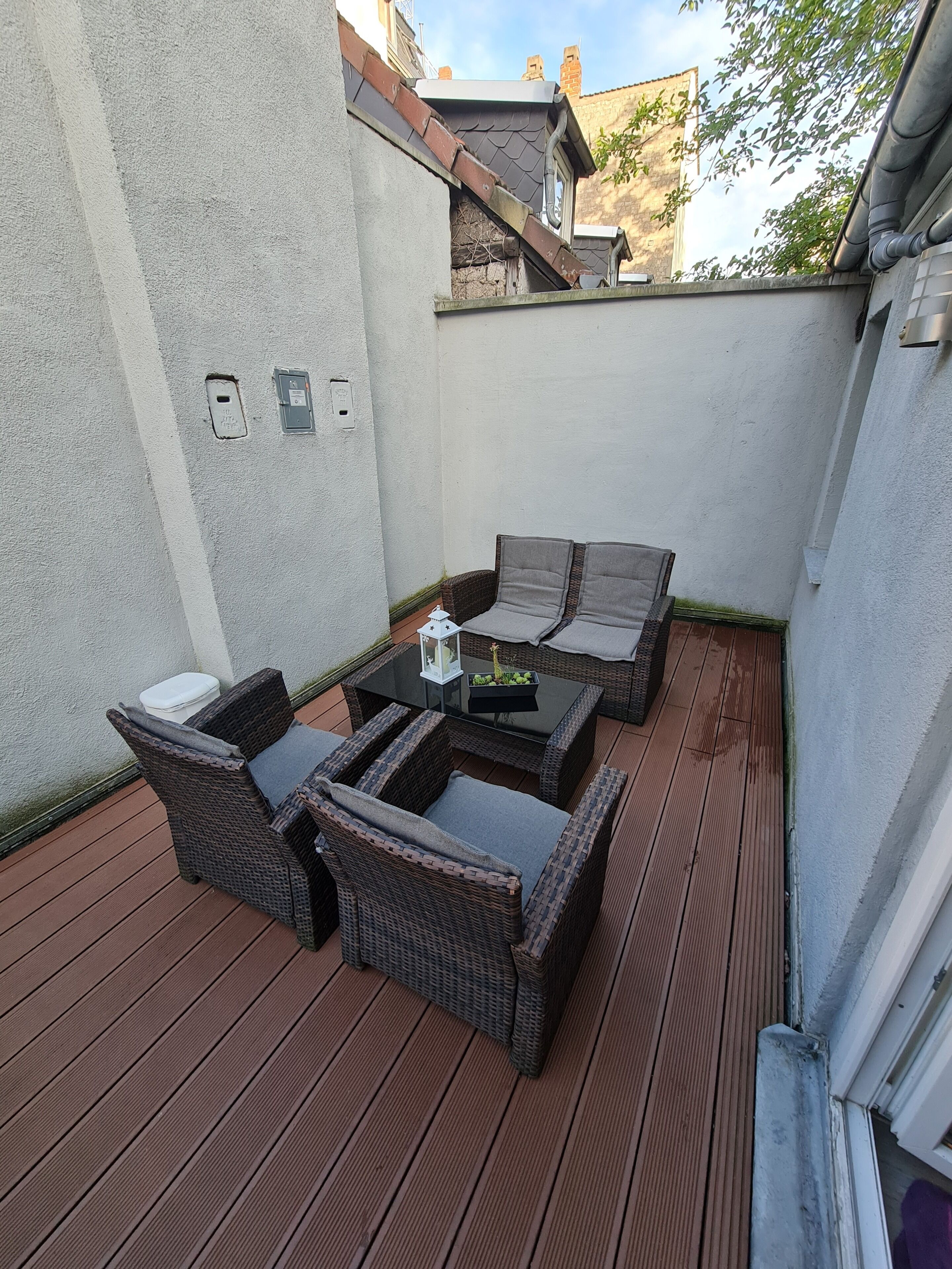 A patio with wicker furniture, a table, and a lantern.