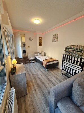 A bedroom with a bed, a bedside table, a lamp, a radiator, a window, and a door. - Cityapartment +terrace up to 4 persons Neuwied city center Rheinprominade (Neuwied)