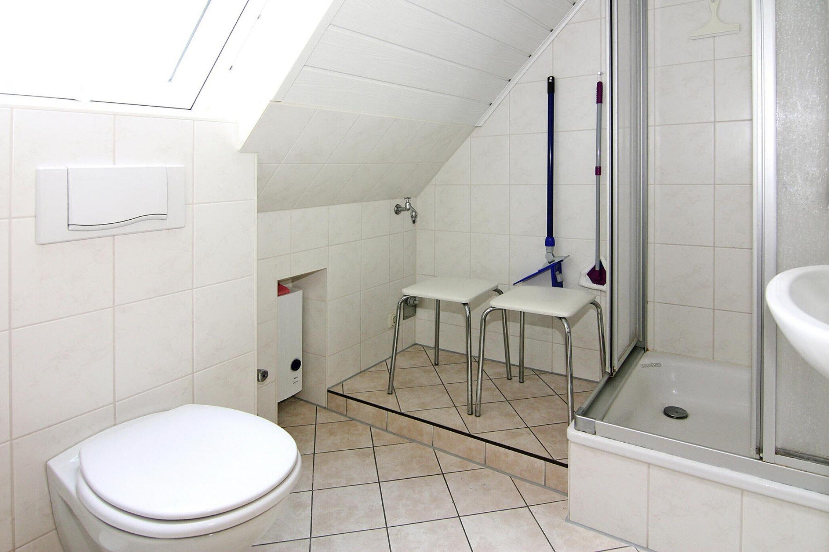 A small bathroom with a toilet, a shower area, and a sink.
