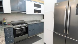 Een moderne keuken met roestvrijstalen apparatuur, grijze kastjes en een granieten werkblad.