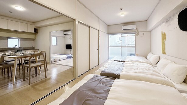 A modern hotel room with a large bed, a dining area, and a kitchen. - Dai3Kuboi 405 (Hiroshima)