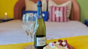 A bed with a wooden headboard, a bottle of champagne, two glasses, and a wooden board with fruit and cream puffs. - La Belle Breisach - PopArty - Colmar/Germany (Volgelsheim)