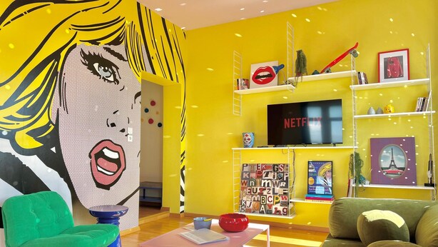 A vibrant living room with a large pop art mural, a green armchair, a brown sofa, and a pink coffee table. - La Belle Breisach - PopArty - Colmar/Germany (Volgelsheim)