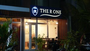 A hotel named "The Rone" with a prominent illuminated sign, a reception area visible through the glass doors, and a parking area with a motorcycle in front. - The R One (Hulhumalé)