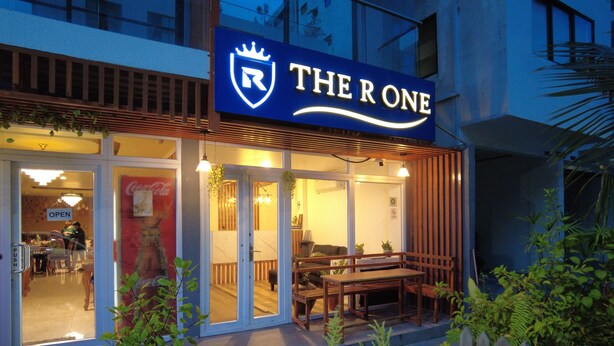 A restaurant named "The R One" with an open entrance, indoor seating, and a wooden outdoor seating area. - The R One (Hulhumalé)